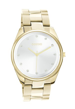 Montre en métal doré avec un cadran argent poli, comportant des index encrés de cristaux et des aiguilles dorées. Bracelet de style adaptable assorti en or.