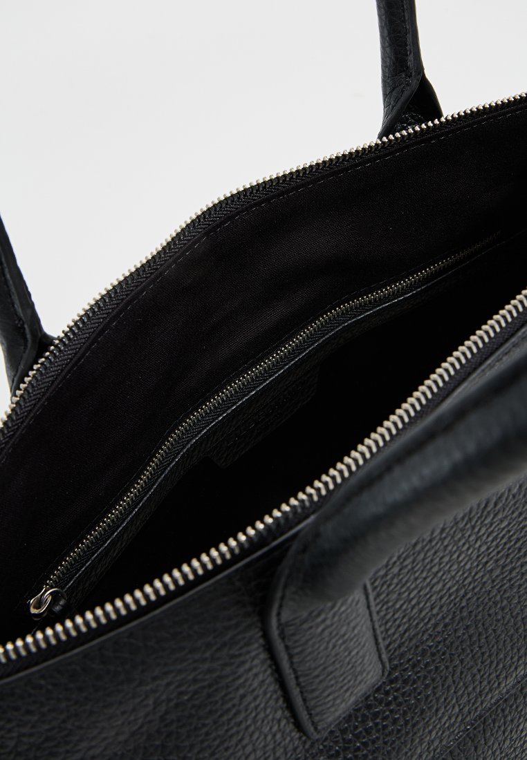 Schwarze Leder-Tote mit strukturierter Oberfläche, ausgestattet mit einem Reißverschluss-Hauptfach und einem glatten schwarzen Stofffutter.