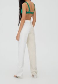 Pantalones de tiro alto en bloques de color blanco y beige con corte recto, hechos de denim, que cuentan con bolsillos traseros y una textura suave.