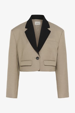 Blazer beige cropped à manches longues, larges revers noirs, un seul bouton noir et deux poches à rabat à l'avant.