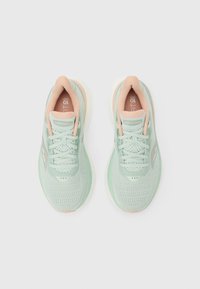 Ζευγάρι αθλητικών παπουτσιών Saucony σε ανοιχτό πράσινο μέντας και ροδάκινο, από ψηλά σε λευκό φόντο.