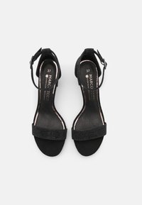 Zwarte hoge hak sandalen met een gestructureerde bovenkant, enkelband en glinsterend detail op de voorband, met een gladde leren binnenzool.