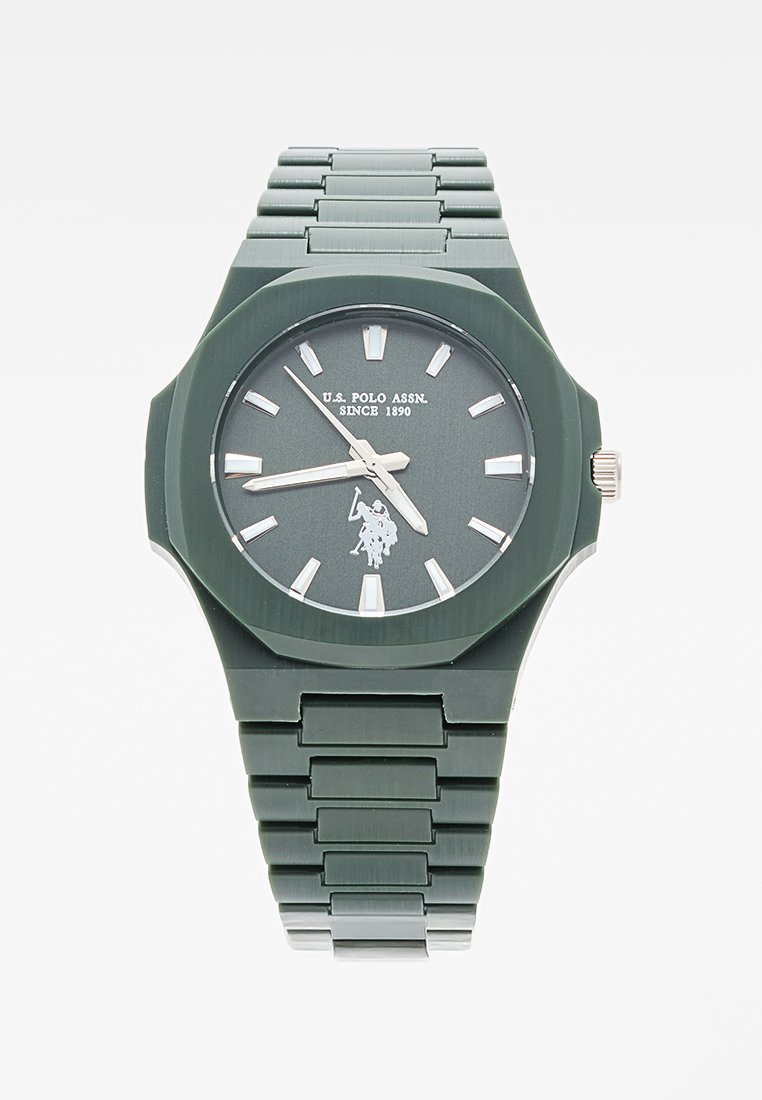 Reloj de pulsera de plástico verde con caja octagonal, marcadores de hora plateados y un logo firmado. Presenta una correa de eslabones y un diseño minimalista.