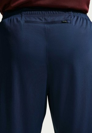 Pantaloni sportivi blu navy con finitura testurizzata e cintura elastica. Presentano una piccola tasca con cerniera sul retro.