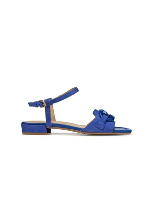 Sandale en daim bleu avec un bout fermé, une bride de cheville et un petit talon bloc. Présente un accent en nœud et une semelle intérieure lisse en contraste.
