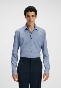 La camicia a maniche lunghe a quadri blu e bianchi presenta un colletto a punta e bottoni frontali, abbinata a pantaloni eleganti scuri. Texture del tessuto liscia.
