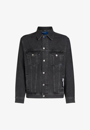 Črna denimska jakna z značilnim ovratnikom, dvema sprednjima žepoma, srebrnimi gumbi in blagovno označbo na levi rokavi.