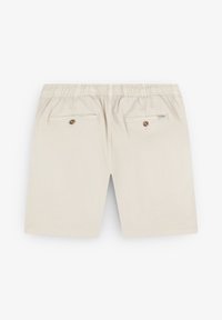Beige bomuldsbukser med elastisk talje, der har to baglommer med knaplukninger og en glat tekstur.