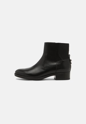 Botte cheville en cuir noir avec un talon empilé bas, un panneau latéral élastique et une bande à tirer à l'arrière.