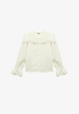 Blouse blanche avec un grand col en dentelle, fermeture à boutons sur le devant, et manches bouffantes avec des poignets smockés. Tissu lisse avec une texture douce.