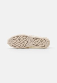 Suela de zapato TOMS de color beige claro con un patrón texturizado y un diseño de tracción en zigzag. Hecha de material flexible, con un diseño superior tejido.