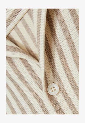Gestreifter Strickstoff in Beige und Creme mit einem Knopfverschluss. Die Textur ist locker gestrickt mit sichtbaren Nähmustern.