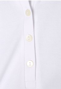 Witte polo shirt met een gestructureerde stof, drie crèmekleurige knopen en zichtbare stiksels. Geen patronen of toevoegingen.