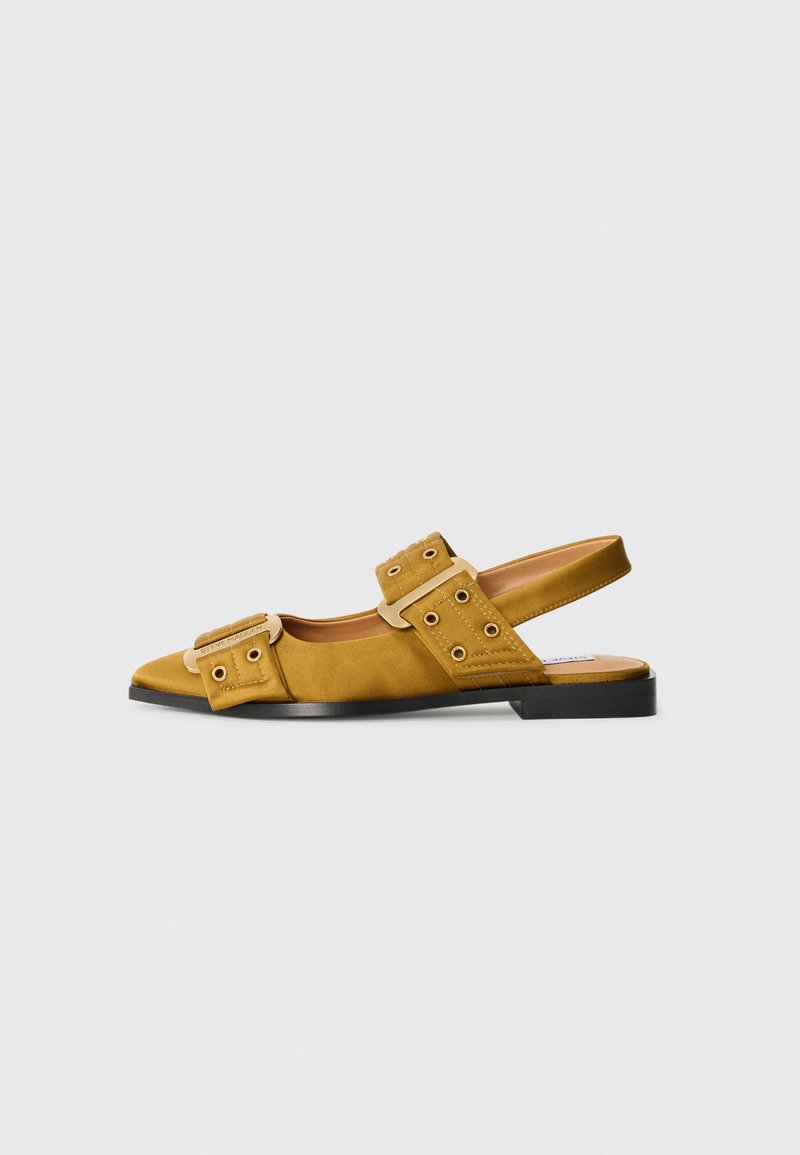 Chaussure à talon slingback en daim jaune avec deux grandes boucles, bout rond, petit talon et semelle noire. Présente des perforations sur les sangles.