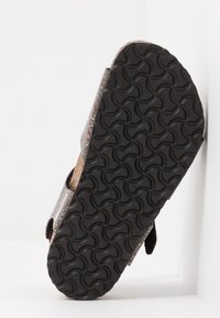 Srebrna sandał z teksturowaną, czarną gumową podeszwą i korkową wkładką. Posiada dwa regulowane paski z błyszczącymi akcentami.