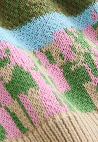 Mehrfarbiger Strickstoff mit einem Muster in Grün, Pink, Hellblau und Beige. Die Textur wirkt weich, mit sichtbaren Nähdetails.