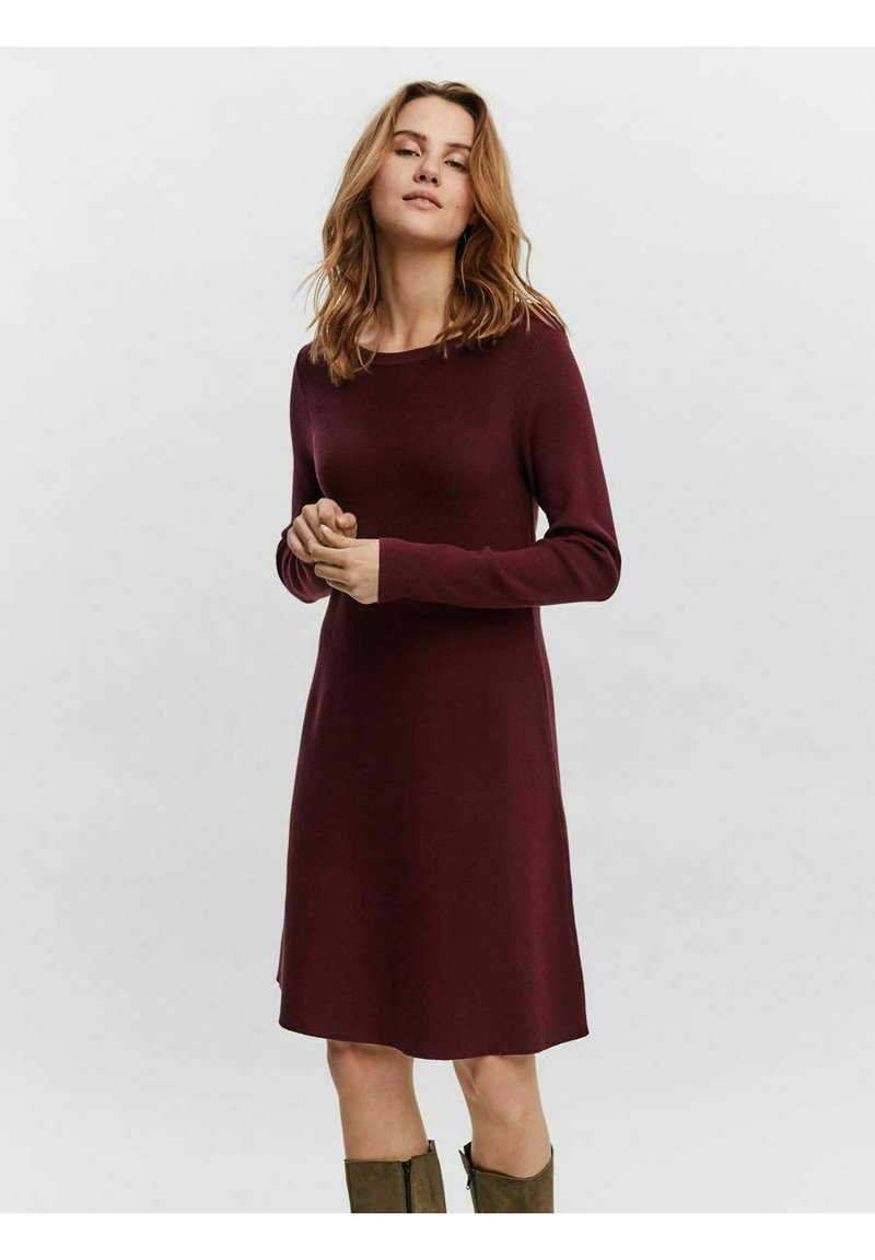 Abito a maglia bordeaux con maniche lunghe, scollo rotondo e vestibilità rilassata, che arriva poco sopra il ginocchio, con una texture liscia e senza fantasie.