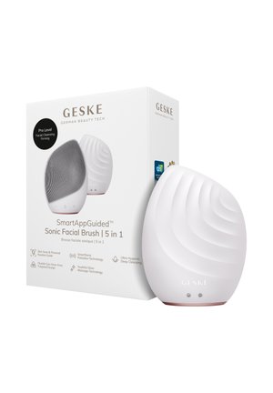 Witte, ovaalvormige GESKE sonische gezichtsborstel met gestructureerd oppervlak naast de doos die de 5-in-1 functies en slimme app-geleiding benadrukt.