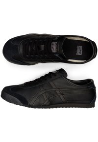 Black athletic shoes with leather and suede materials, rounded toe, flat rubber sole, and distinctive side stripes and branding. Laced design.