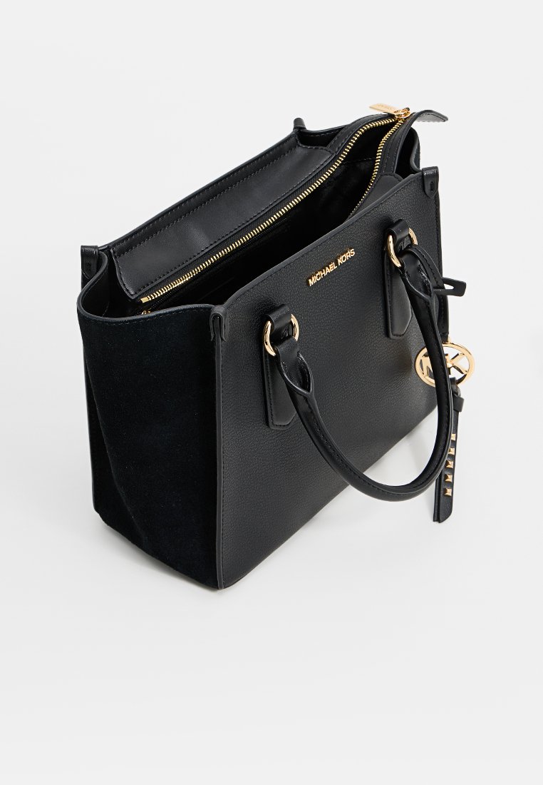 Borsa Michael Kors nera con cerniera dorata, manici, logo e charm MK, parzialmente aperta che mostra i compartimenti interni.