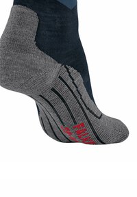 Primo piano di una calza blu navy e grigia con strisce nere e il testo rosso "FALKE" sulla suola, che mette in evidenza le aree rinforzate del tallone e delle dita.