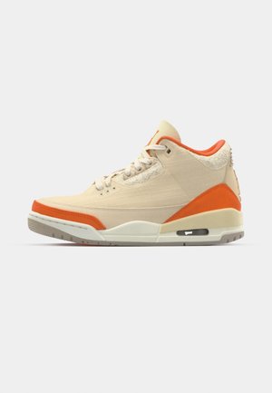 Beige sneakers med orange accenter, overdækning i lærred, teksturerede detaljer ved hælen, og en synlig luftenhed i sålen.
