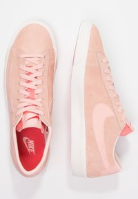 Rosa mockaskor med vita gummisulor och matchande snören. Har en stor, rosa Nike-swoosh och en röd insida.