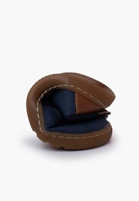 Scarpa slip-on in pelle marrone e tessuto blu, piegata per la conservazione. Presenta suola in gomma texturizzata e cuciture decorative lungo i bordi.