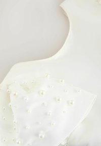 Witte jurk met een gestructureerde lijfje voorzien van clusters van parelachtige versieringen en een gladde, naadloze afwerking langs de halslijn.