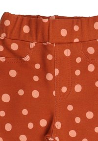 Rust-colored leggings with a stretchy waistband, featuring scattered pink polka dots and pockets for added detail and design.
