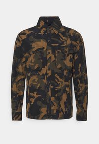 Camicia camouflage con due tasche frontali, caratterizzata da un motivo multicolore marrone e nero, chiusura con bottoni e colletto.