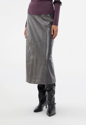 Grå metalisk midiskørt med en glat tekstur, der har en lige skæring og en subtil glans. Sammen med tætsiddende sorte knæhøje støvler.