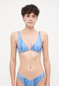 Blå bikini-sett med trekantet topp og høyt skjært bunn, med blomster- og stripete mønstre, laget av glatt og lett stoff.