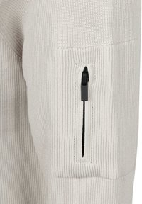 Lichtgrijze geribbelde trui-detail dat de textuur van de stof toont, met een ritszak met een zwarte rits op de bovenkant van de mouw.