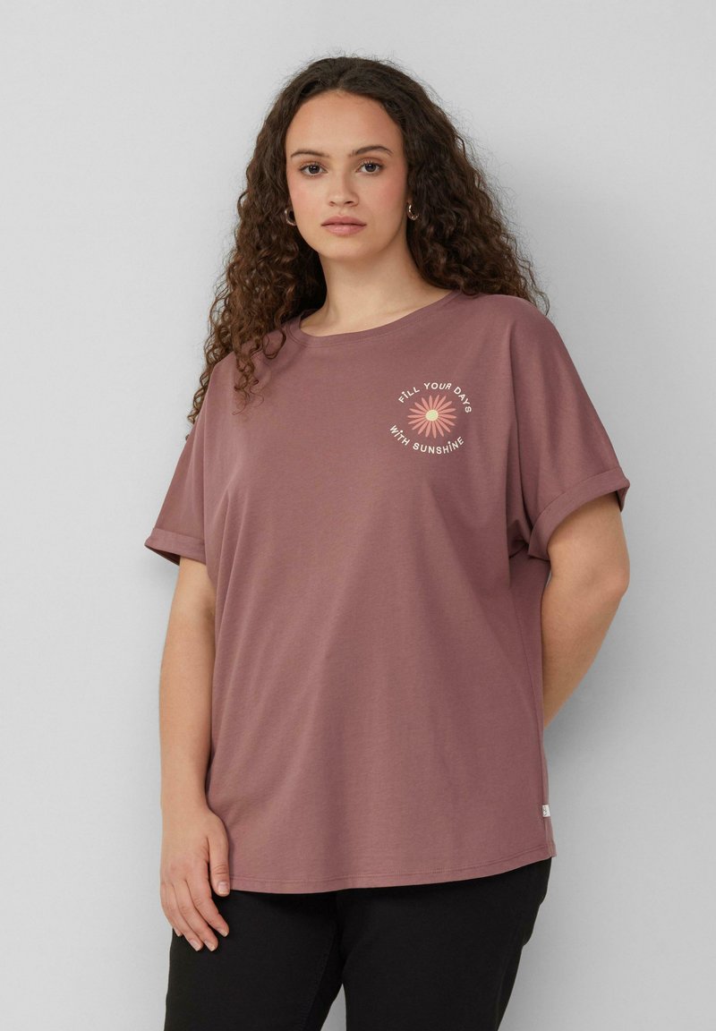 Roze katoen T-shirt met opgerolde mouwen, voorzien van een bloemenafbeelding en de tekst "VUL JE DAGEN MET ZONNESCHIJN" in pastelkleuren.
