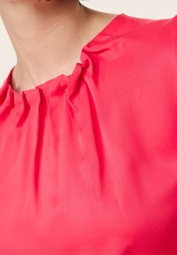 Fuchsia bluse med samlet halsudskæring, fremstillet af blødt, glat stof og med en tætsiddende design, der fremhæver tekstur og livlig farve.