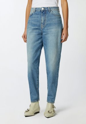 Jeans azzurri chiari a vita alta con taglio dritto, lavaggio sbiadito, design a cinque tasche e chiusura con bottone metallico, abbinati a stivali grigi chiari.