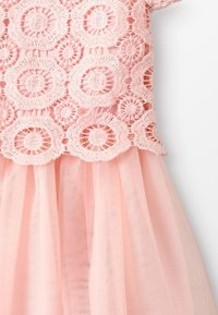 Rosa klänning med cirkulär spetsbroderi på bysten och en mjuk tyllkjol, vilket ger ett delikat och luftigt utseende.