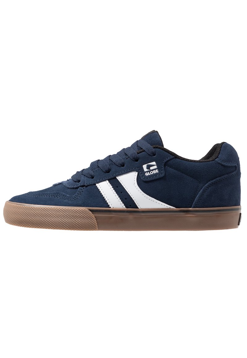 Navy blue suede sneaker with white stripes, round toe, flat brown rubber sole, and black interior padding. Features laces and logo on side.