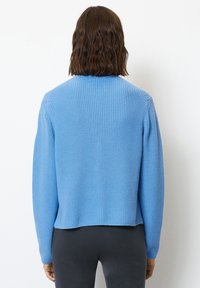 Ljust blått stickat tröja med ribbad textur, kort längd och långa ärmar, med rund halsringning och enkel design.