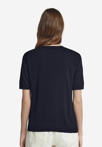 Marinblå t-shirt med kort ärm och rund halsringning, mjukt material och avslappnad passform, med uppvikta ärmar och en enfärgad design.