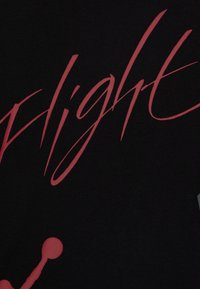 Schwarzes T-Shirt mit übergroßem, stilisiertem roten Text, der "Flight" buchstabiert, mit kühlem Grafikdesign und glatter Textur.