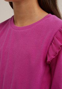 Fuchsiastrimmad tröja med rund halsringning och rynkade detaljer på axlarna, som visar en mjuk textur och en figursydd design.