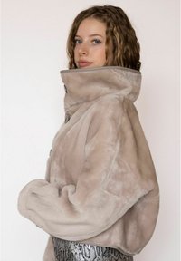 Jas van nepbont in lichtbeige met een hoge kraag, oversized mouwen en een licht cropped ontwerp, met grote knopen aan de voorkant.