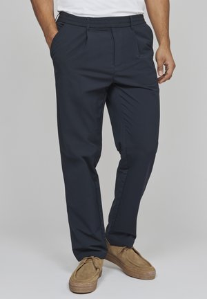 Navy blauwe relaxed-fit broek met elastische tailleband, zijzakken en een gladde, lichte stof. Accentuert door een eenvoudig design.