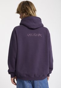 Purple hoodie with a textured finish, featuring a pink graphic design on the back. It has a kangaroo pocket and ribbed cuffs. Casual fit.