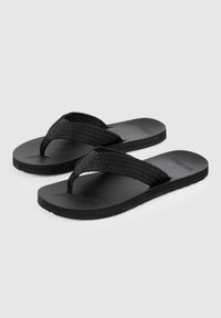 Svarta flip-flops med vävda tygremmar och en platt, texturerad gummisula. Designen är minimalistisk utan synlig märkning.