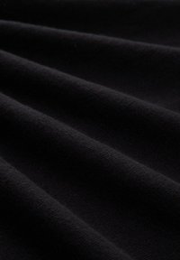 Schwarzer Stoff mit einer weichen, strukturierten Oberfläche. Das Material weist subtile Wellen und Variationen in der Tiefe auf, die das glatte Finish betonen.