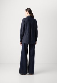 Navyblauwe linnen shirt met een casual pasvorm, lange mouwen, knoopmanchetten en een rugplooi, gecombineerd met ruime denim broek.