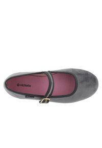 Zapato plano gris con acabado texturizado, que presenta un acento de hebilla dorada en una correa al estilo Mary Jane y un forro interior rosa, de la marca "Victoria".